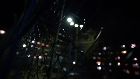 malla de metal. cancha de baloncesto vacía por la noche a la luz de las linternas. valla de la prisión.