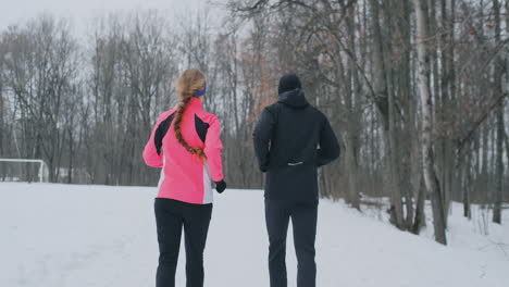 positive beautiful young healthy couple running with sportswear through the forest in the winter morning