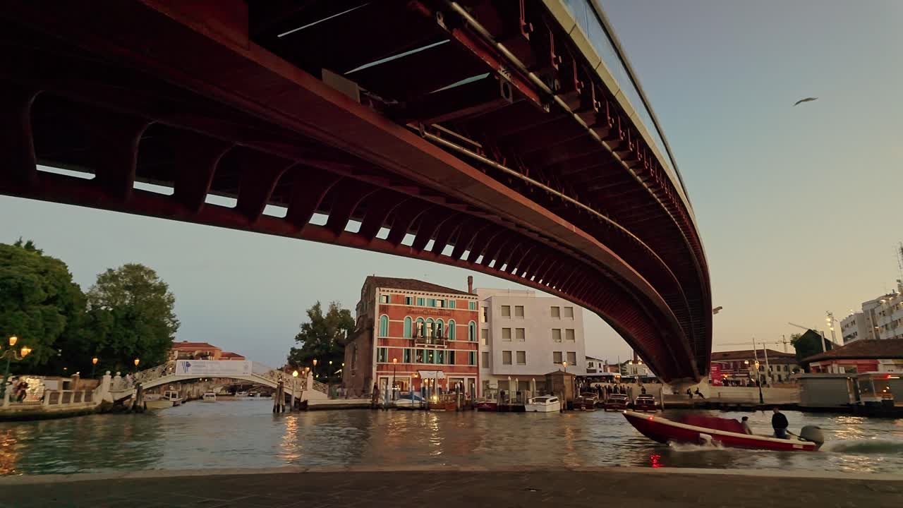 Venetian boats pass under Constitution bridge walkway at Golden hour
