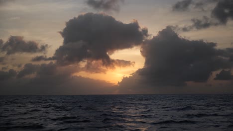 sun setting behind clouds above the ocean in 4k