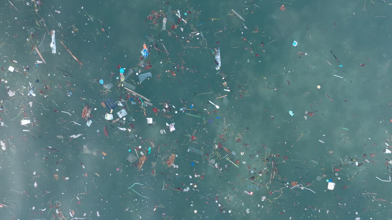 Top down drone shot of polluted water filled with plastic trash and dead coral reef in the turqouise tropical water of Balangan Beach Uluwatu Bali Indonesia