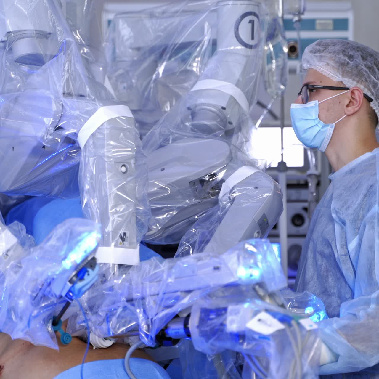 Surgical procedure of robotic machine. Medical robot performs an operation in clinic. Doctor in medical uniform stands near modern surgical equipment.