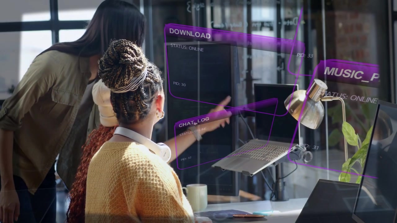 Seated woman responding to peer pointing, reaching for monitor to adjust tech HUD panels pulsing