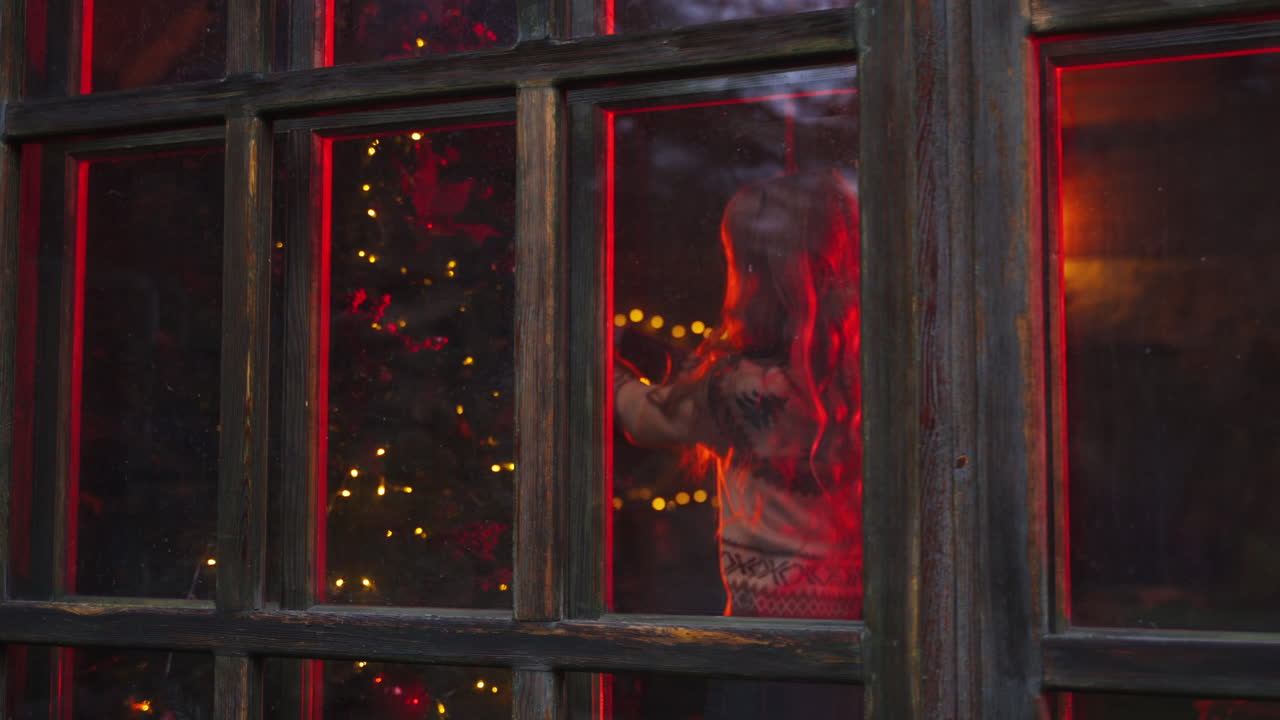 Young beautiful blonde woman decorates a Christmas tree. New Year decorations. Feast preparations. Girl in knitted sweater. Portrain of a nice girl.