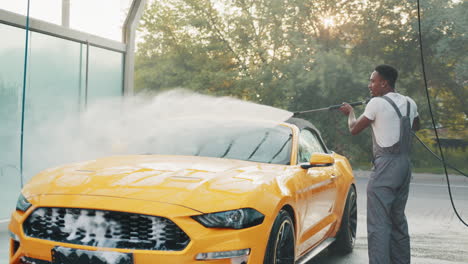 trabajador de lavado de coches detallando un descapotable amarillo
