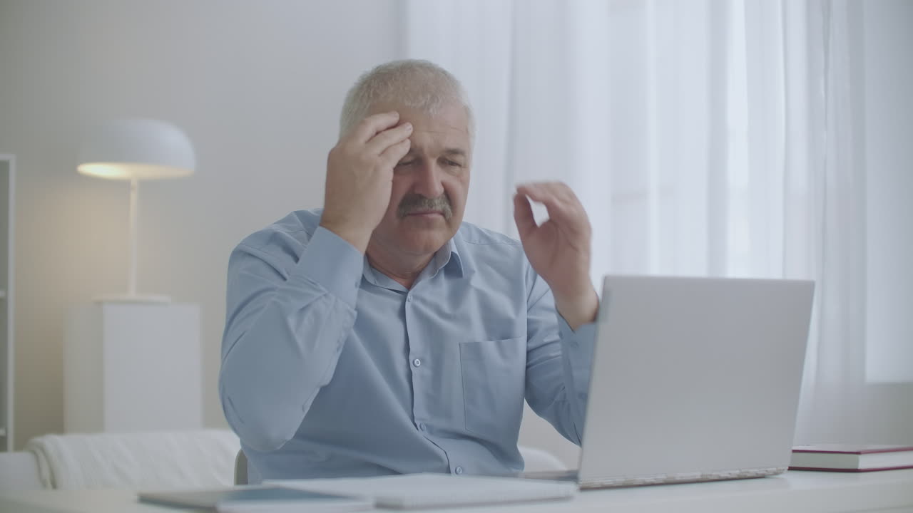 l'uomo sta lavorando con il portatile sente un improvviso mal di testa tocca la fronte con le mani sovraccarico e stanchezza