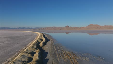 bonneville salt flats with mountains reflecting in water surface of lake in winter season