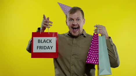hombre sonriente mostrando la inscripción de black friday en las bolsas de compras, celebrando, regocijándose de buenos descuentos