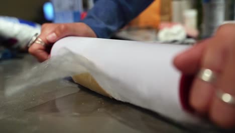 A-rolling-pin-flattening-a-circle-of-sugar-cookie-dough-from-the-side-in-order-to-bake-Holiday-Christmas-cookies-on-a-cold-winter-night