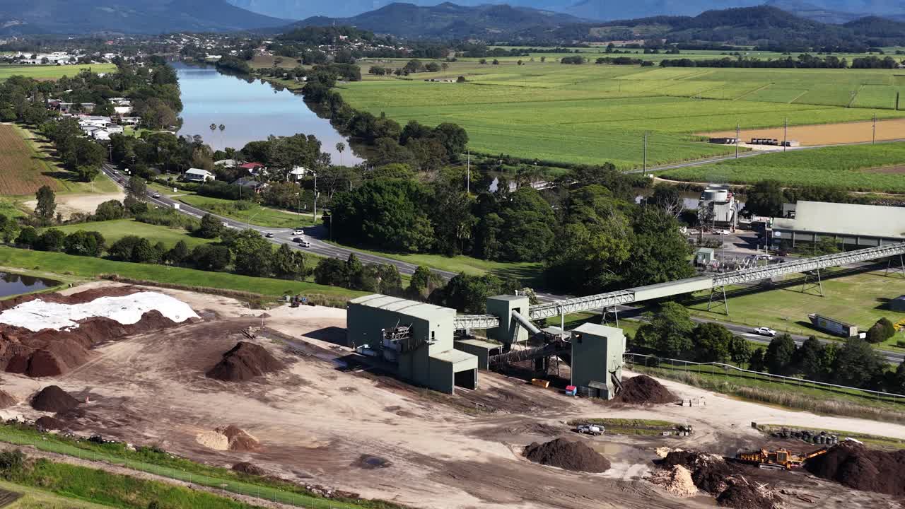Aerial footage captures a sugar mill surrounded by lush greenery and distant mountains under clear skies