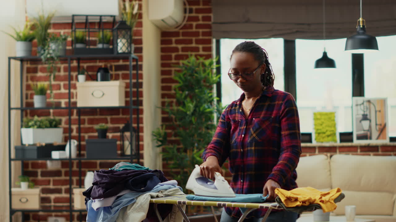 Afro-americana se divertindo ao passar roupa na sala de estar
