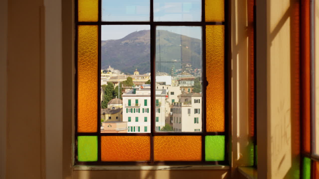 Vista di Genova attraverso vetri colorati di una finestra con montagne sullo sfondo