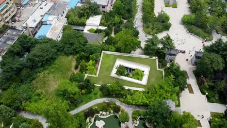 aerial cinematic bird's eye view with forward dolly of a pond on a sunny afternoon at huancui lou park, weihai city, china