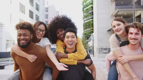 three young adult couples having fun piggybacking in a city street, close up