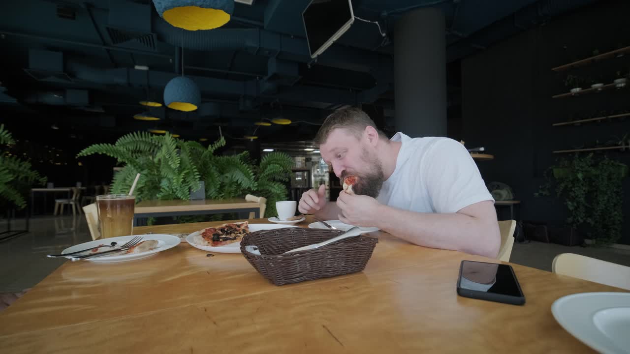 hombre comiendo pizza en un café