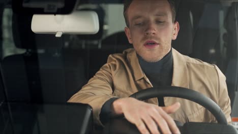 handsome man evaluates the new interior while sitting in the car behind the wheel