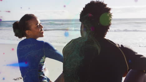 sitting on beach, two people relaxing under sun with ocean view