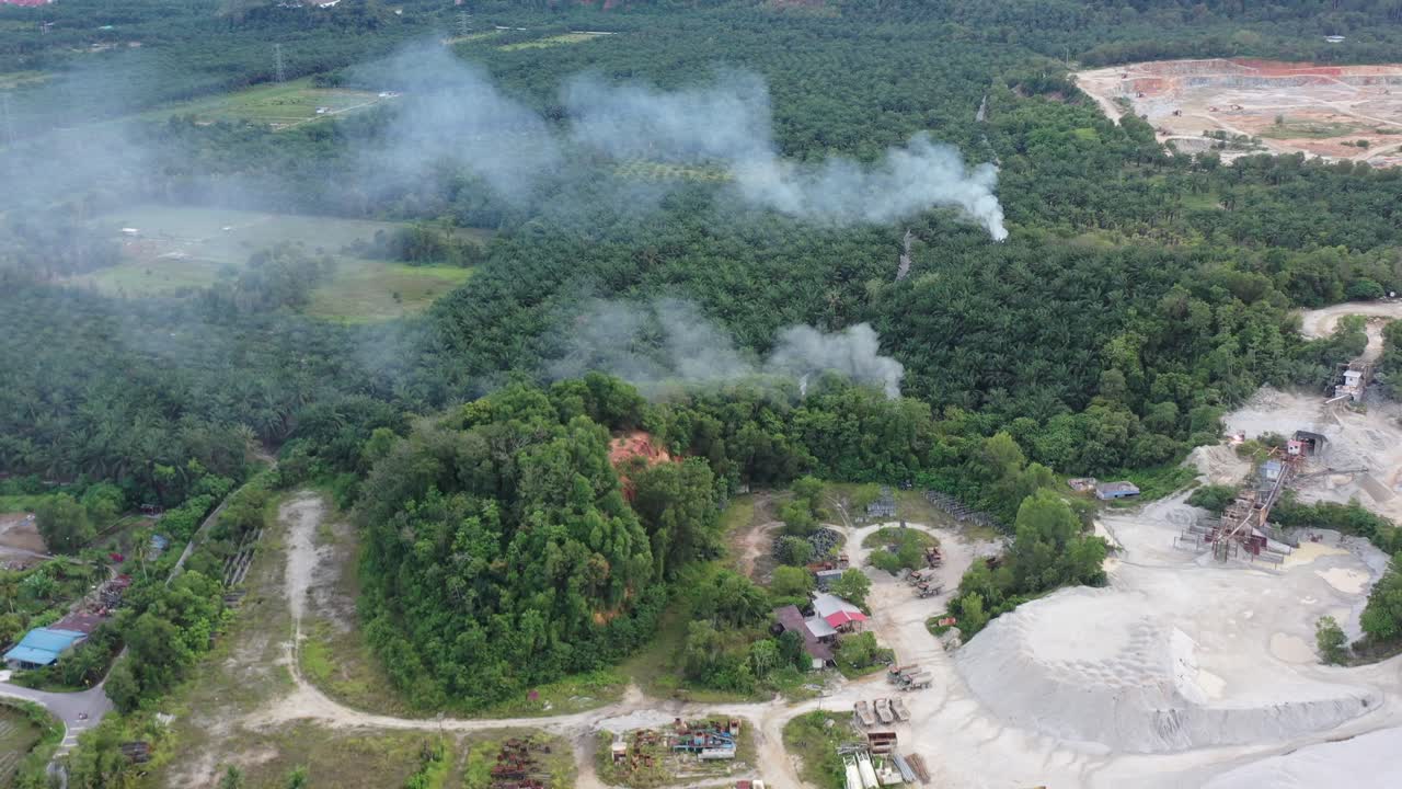 vista de pájaro de la contaminación del aire humeante producida por la combustión al aire libre por la industria de plantaciones de palmeras ubicada junto a una cantera activa en el distrito de manjung, perak, sudeste asiático