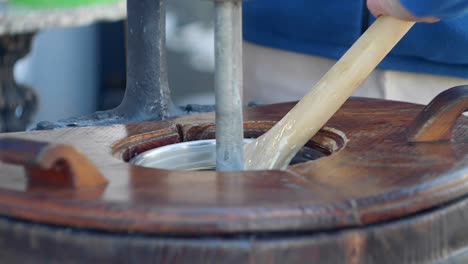 person removing vanilla ice cream with wooden spoon from vintage machine