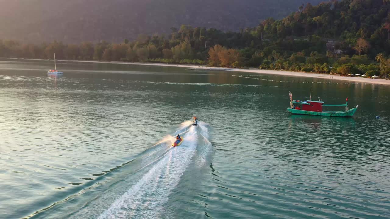 아름다운 일몰 황금 시간, 말레이시아, 동남아시아에서 랑카위 섬의 판타이 콕 해변을 따라 바나나 보트를 타고 낮은 수준의 파노라마 곡선 공중 샷