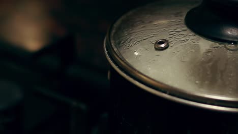 Steam-and-condensation-on-a-transparent-cooking-pot-lid-against-a-dark-background,-shows-the-peaceful-moment-of-daily-home-life