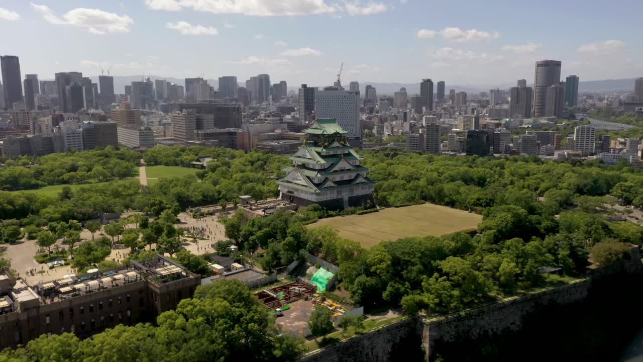 Aerial of Osaka Castle with trees, park, moat, skyscraper, and city in Osaka, Japan
