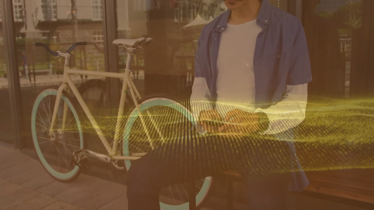 Man holding phone outside storefront on bench, showcasing yellow digital wave for tech marketing