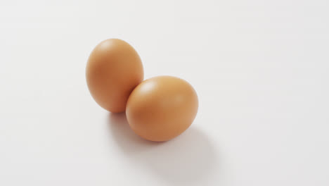 close up view of of two brown eggs with copy space on white surface