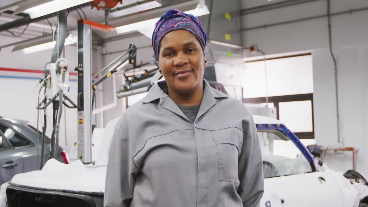 Mécanicienne automobile afro-américaine regardant l'appareil photo et souriant.