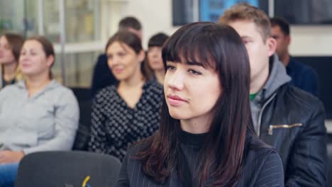 People at meeting in the office. Beautiful young woman sitting among viewers in the conference hall. Entrepreneurship concept.