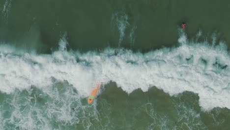 An-amateur-surfer-falls-while-attempting-to-ride-a-wave-at-a-beach-with-transparent-green-waters,-showcasing-the-challenges-and-excitement-of-learning-to-surf