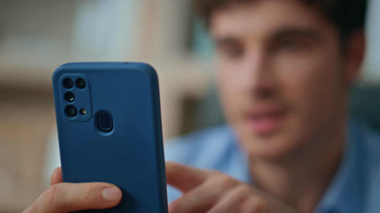 Smiling man playing cellphone at morning apartment close up. Happy businessman