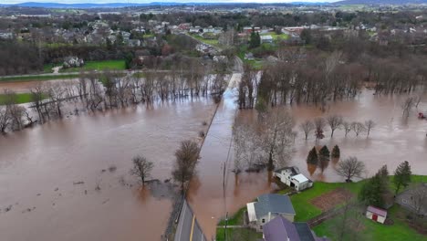 Aerial-orbiting-shot-of-flooded-street-with-brown-murky-water-after-heavy-rain