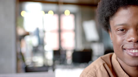 Portrait-of-happy-african-american-man-with-afro-sitting-on-sofa-at-home,-slow-motion,-copy-space