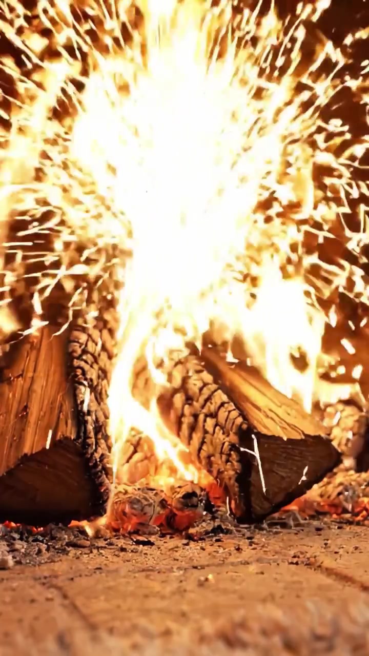 Un primo piano accattivante di un fuoco scoppiettante con cataste di legna, che irradia calore e intensità in un accogliente ambiente camino.