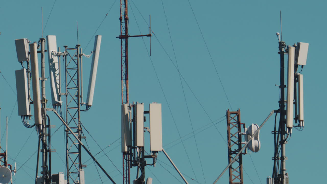 Telecommunication antennas and towers installed on a rooftop against a clear blue sky