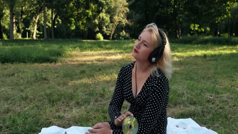hermosa rubia sentada en la valla de hierba y escuchando música