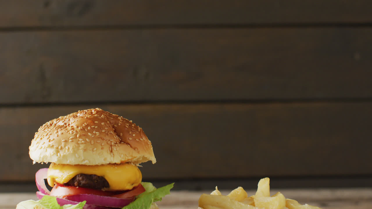 video de hamburguesa con queso y papas fritas contra un fondo de madera rústico con espacio para copiar