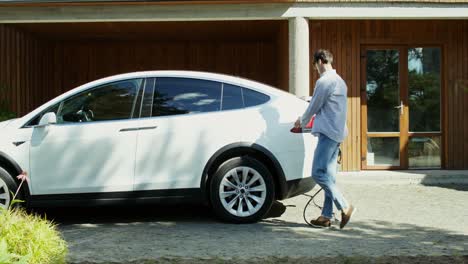 person charging electric car at home