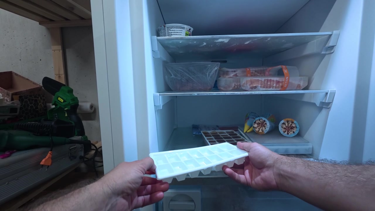 POV em primeira pessoa colocando uma forma de gelo no congelador. Ideal para verão, armazenamento de alimentos, refrigeração e conceitos domésticos