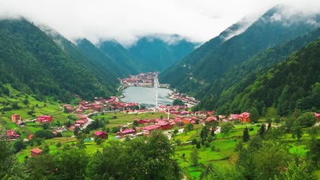 aerial zoom out vie stunning mountain lake with turquoise water, green trees and beautiful homes, uzun gol in karadeniz