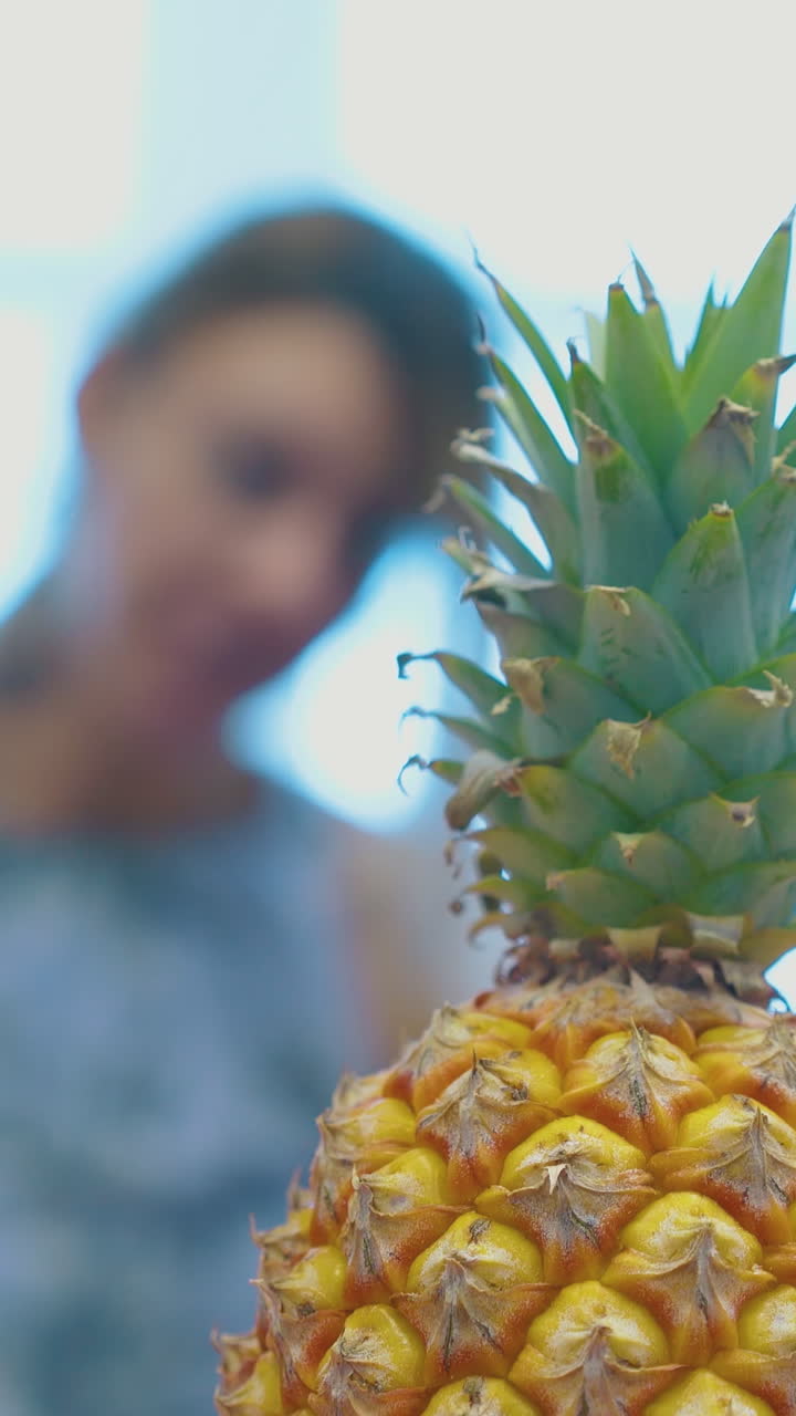 fresh yellow pineapple with bright green top against blurred relaxed women eating fruits extreme close view