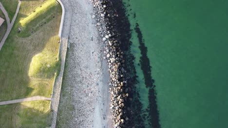 aerial-view-around-kronborg-castle-denmark,-near-copenhagen,-we-see-the-waves-crashing-on-the-rocks-of-the-beach