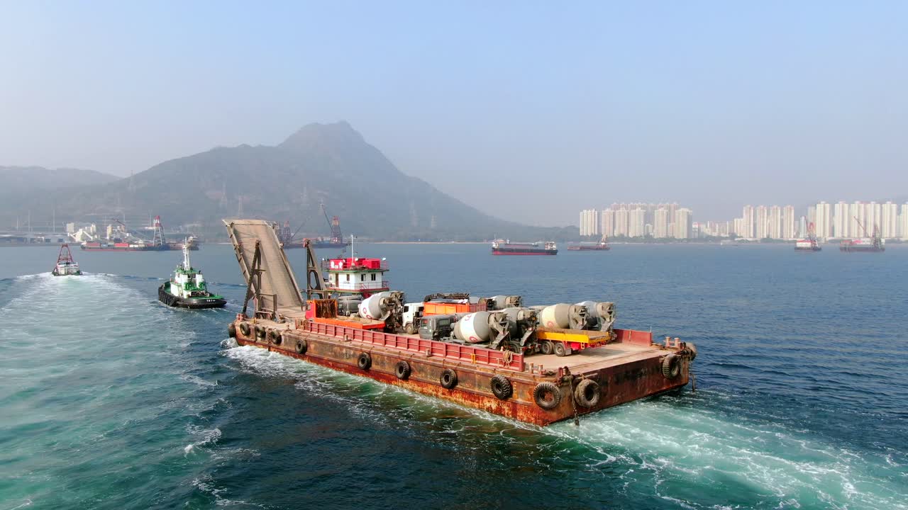 홍콩 만의 예인선으로 항구로 끌려간 콘크리트 믹서 트럭을 실은 바지선, 공중 전망