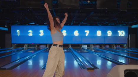 A-Hispanic-woman-jumps-joyfully-looking-into-the-camera-celebrate-the-victory-in-slow-motion.-Throw-in-the-bowling-alley-to-make-a-shoot.-Victory-dance-and-jump-with-happiness.