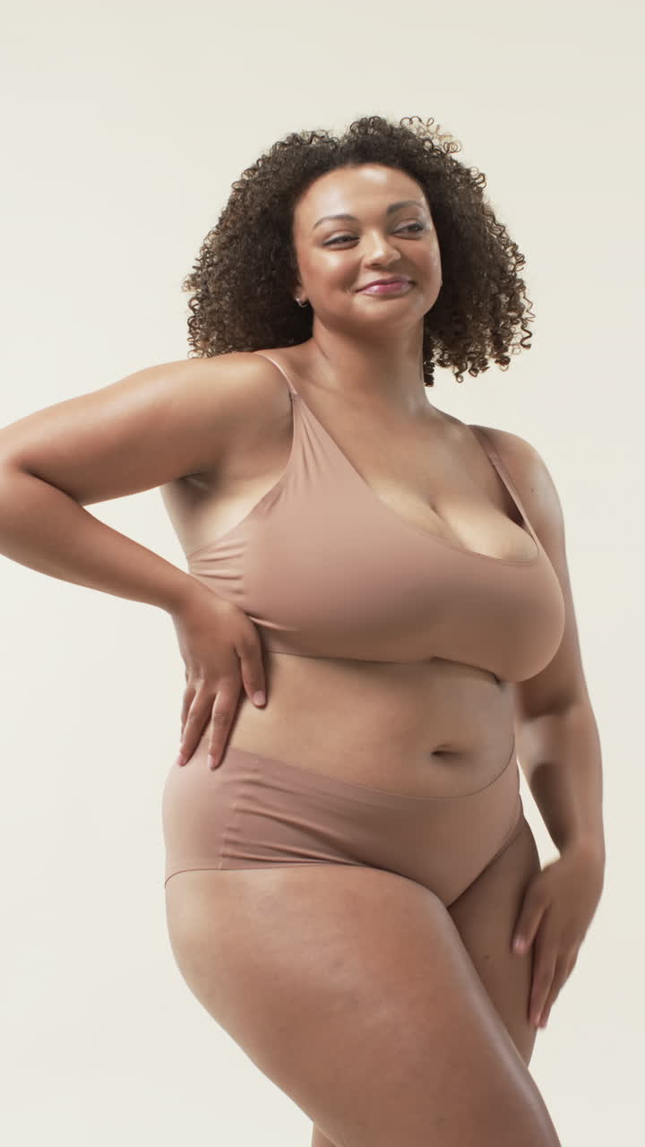 Video verticale: Donna curvy sorridente che posa con sicurezza in biancheria intima, abbracciando la positività corporea.