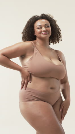 vertical video: smiling plus size woman posing confidently in underwear, embracing body positivity
