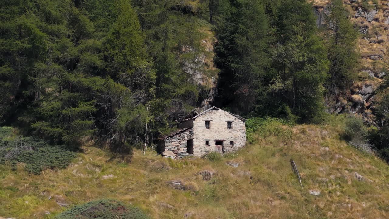 Close-up orbiting right aerial view of a mountain house in Valtournenche, Aosta Valley, Valle d’Aosta, surrounded by dense pine forest