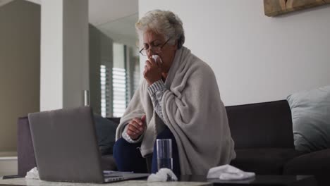 Sick-african-american-senior-woman-coughing-while-having-a-video-call-on-laptop-at-home