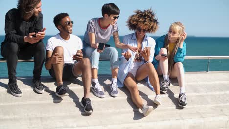 contemporary diverse friends with smartphones on seafront